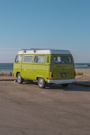 green volkswagen t-2 on brown soil near body of water during daytime