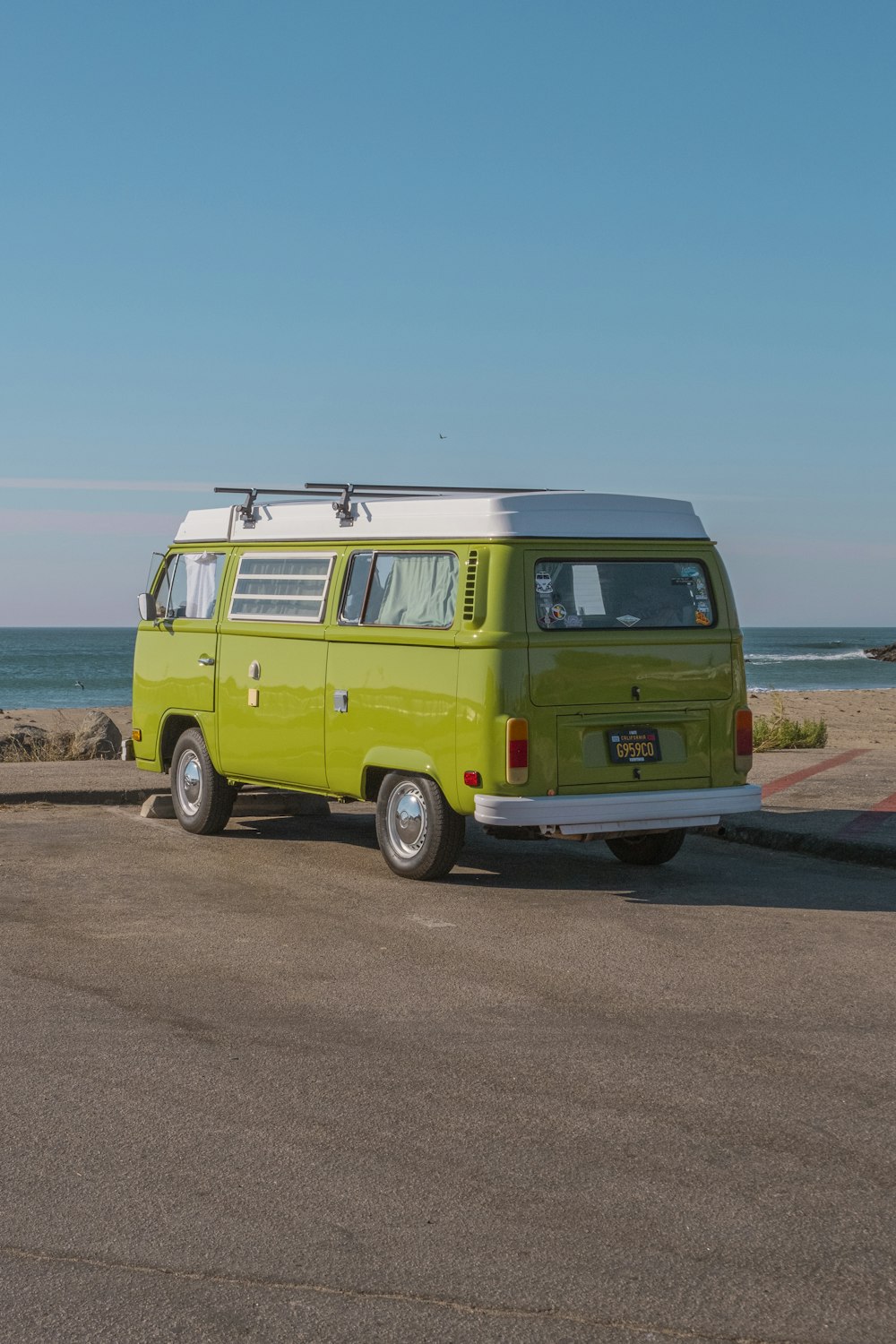 Volkswagen T-2 vert sur sol brun près d’un plan d’eau pendant la journée