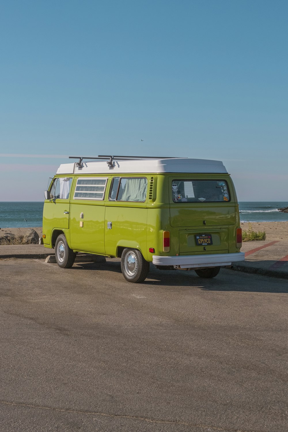 green volkswagen t-2 on brown soil near body of water during daytime