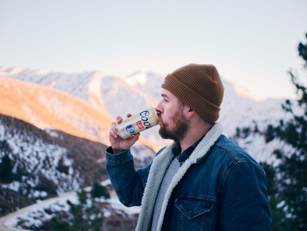 man in blue denim jacket drinking beer