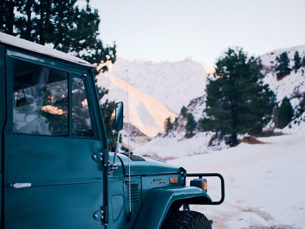 green jeep wrangler on snow covered field during daytime