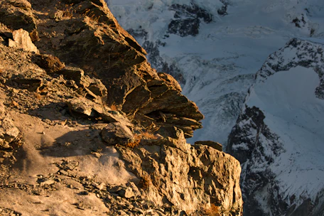 A powerful controlled blasting operation in a rugged mountainous terrain at sunrise.
