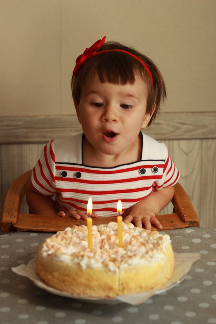 image is of a child blowing out candles on a cake