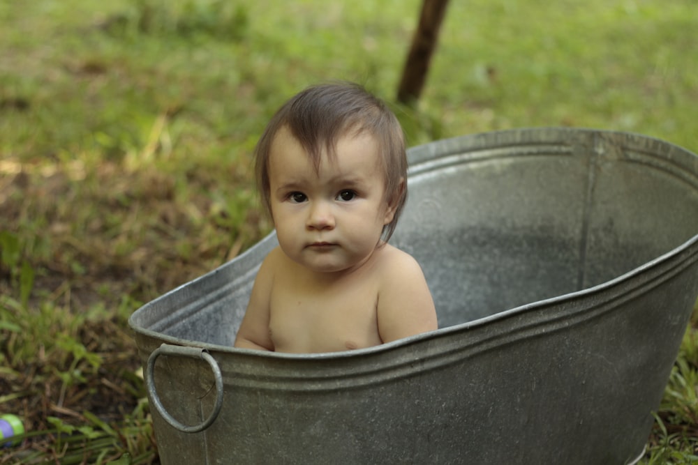 topless baby in blue plastic bucket