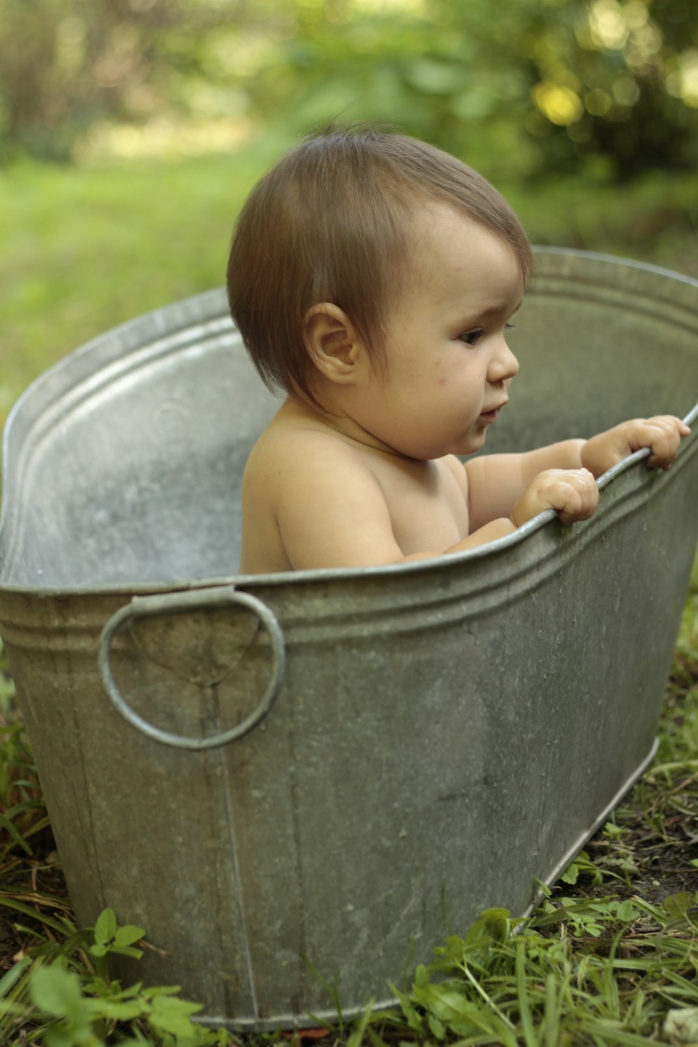 topless baby in grey plastic bucket