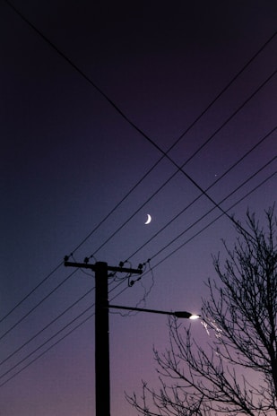 black electric post under blue sky during night time