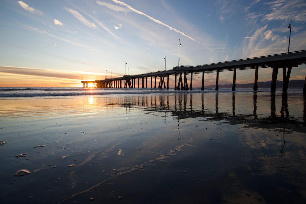 silhouette of bridge over water during sunset