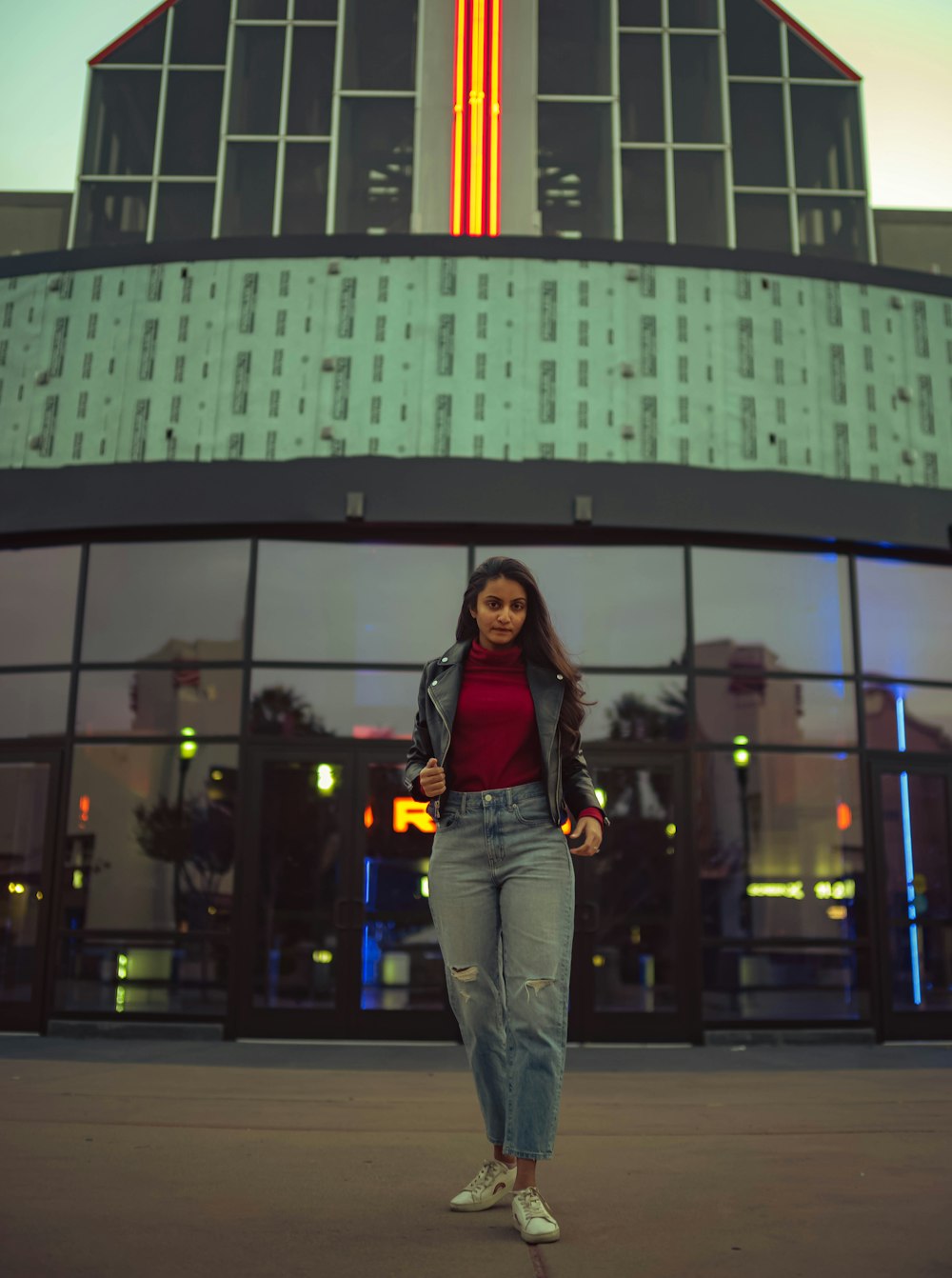 woman in black long sleeve shirt and blue denim jeans standing near building during night time