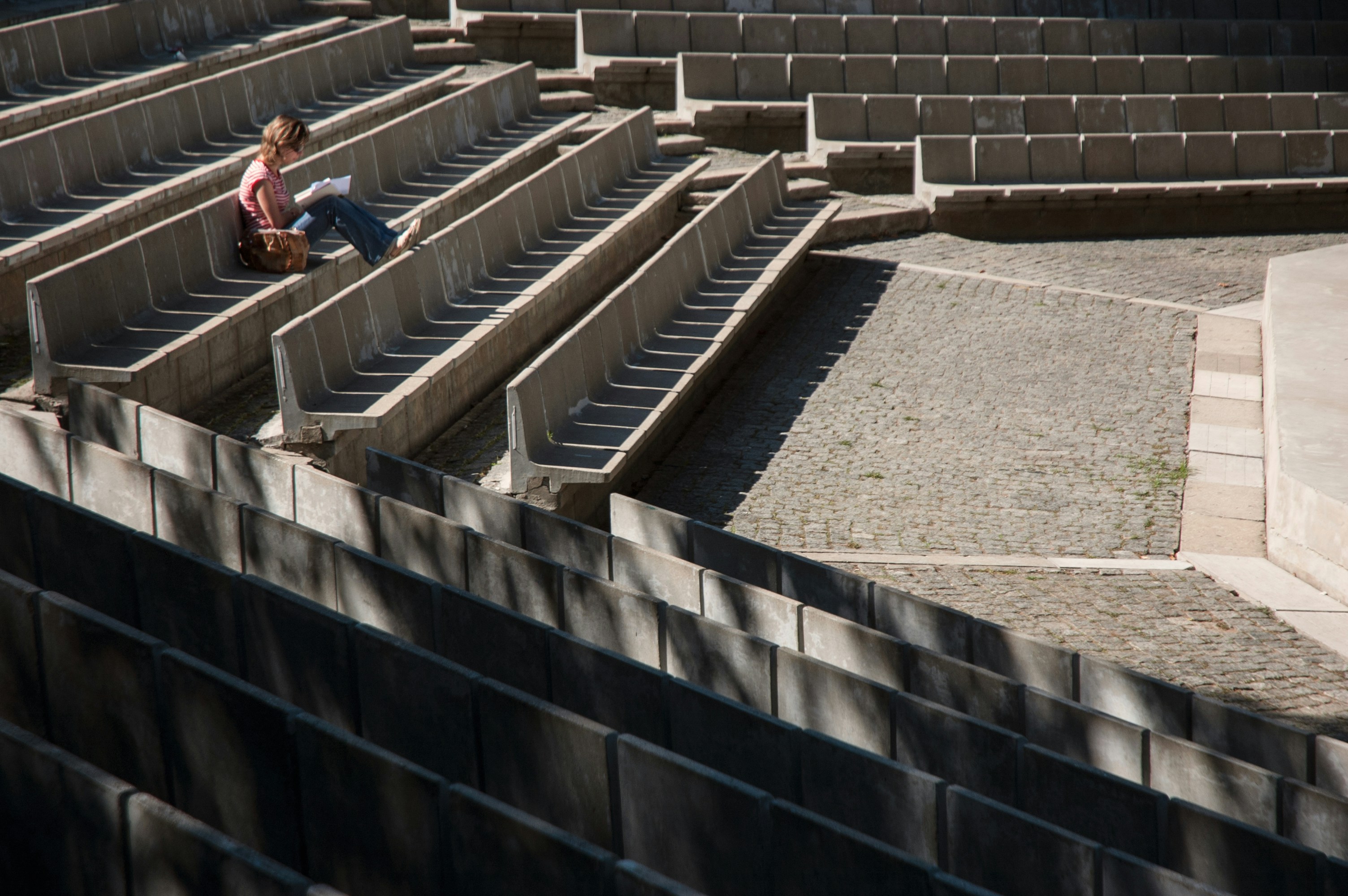 man in red shirt sitting on brown concrete stairs during daytime
