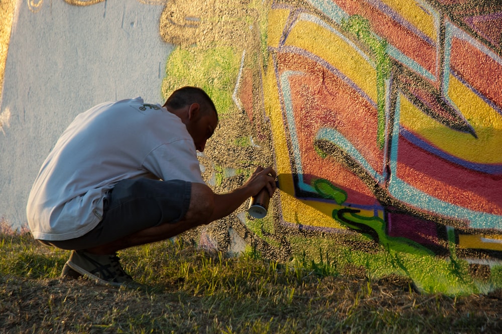 Homme en polo blanc et pantalon noir assis sur un terrain d’herbe verte