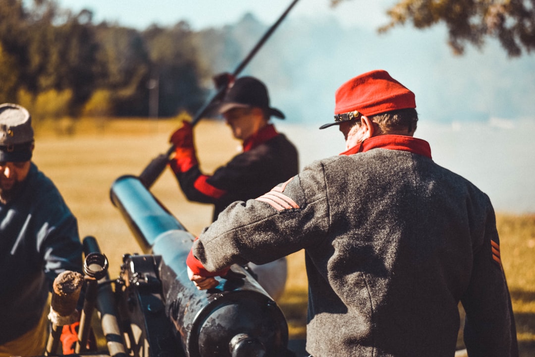 man in black jacket and orange helmet holding black rifle