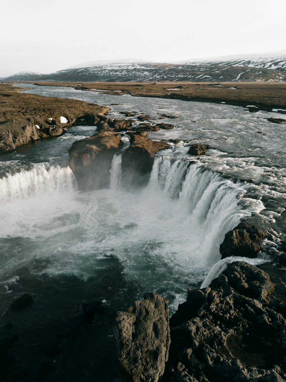 water falls on brown rocky mountain during daytime