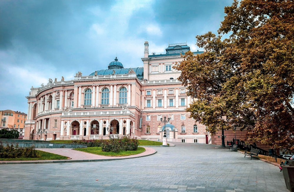 Weißes und braunes Betongebäude in der Nähe von grünen Bäumen unter blauem Himmel tagsüber