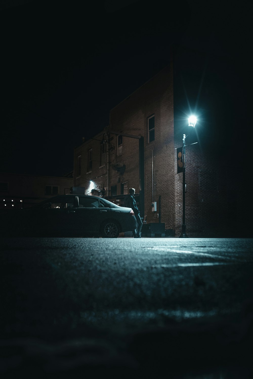 white car parked beside brown brick building during night time