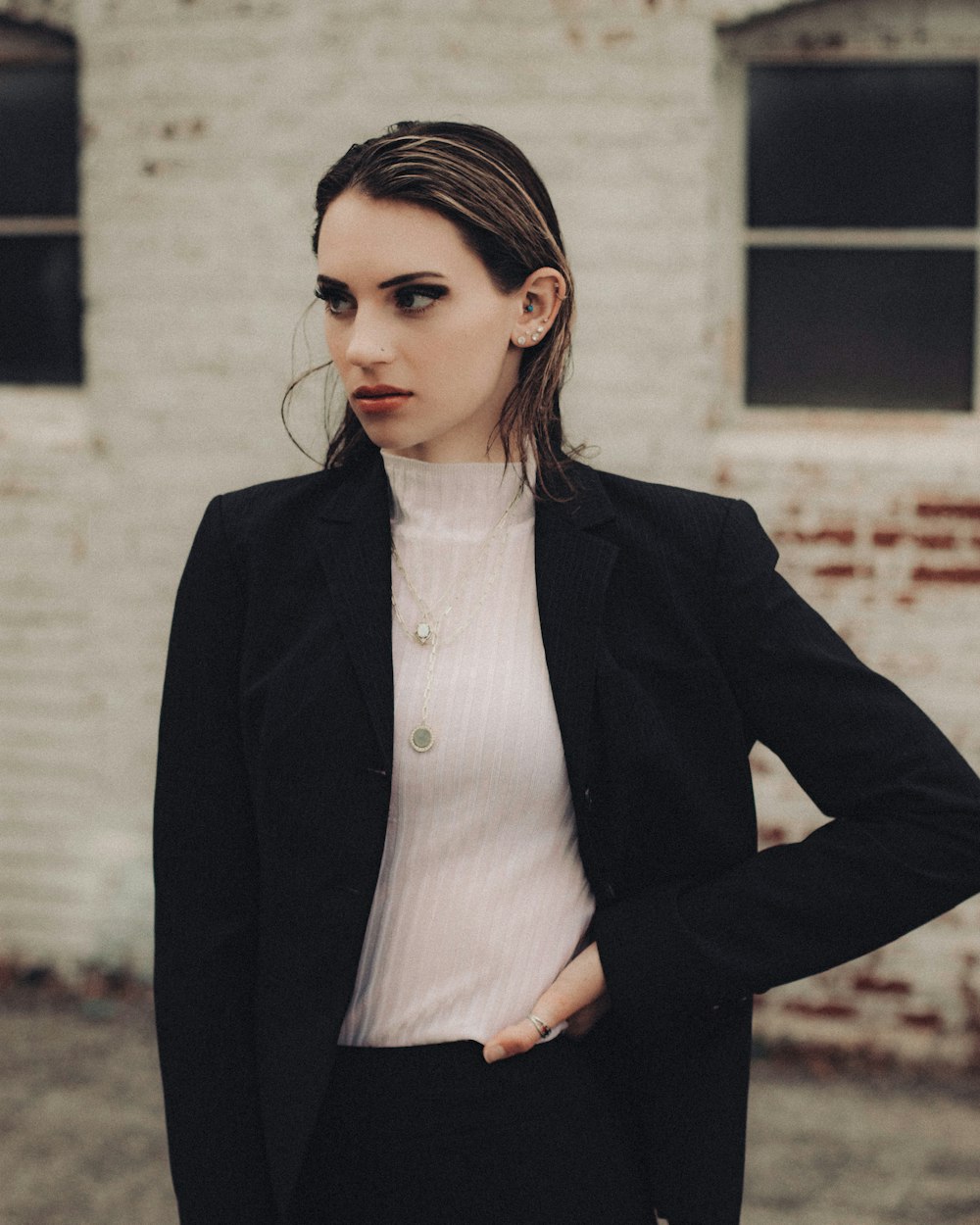woman in black blazer standing near white wall