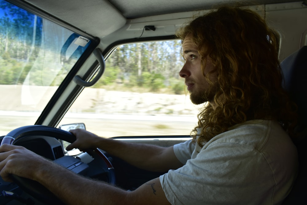 a man with long hair driving a truck