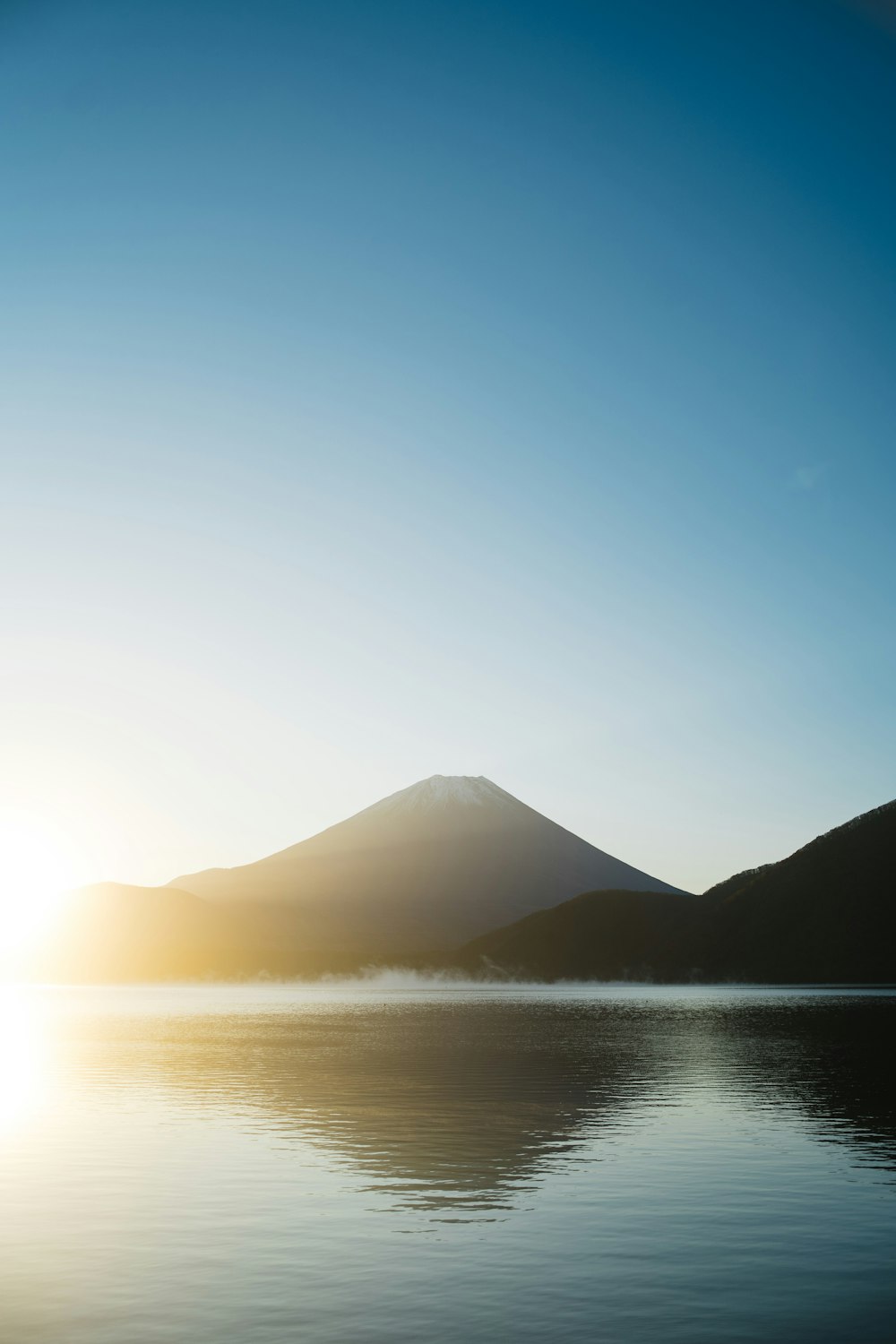silhouette of mountain near body of water during daytime