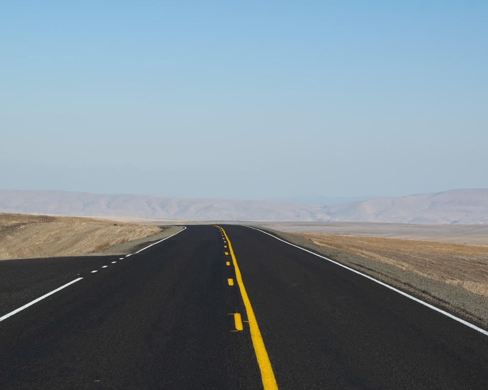 Schwarze Asphaltstraße unter blauem Himmel tagsüber