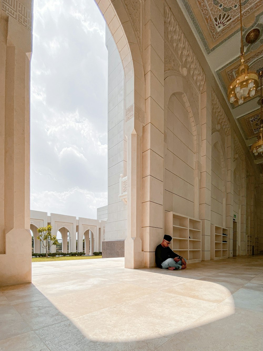 Femme en hijab noir assise sur des carreaux de sol blancs