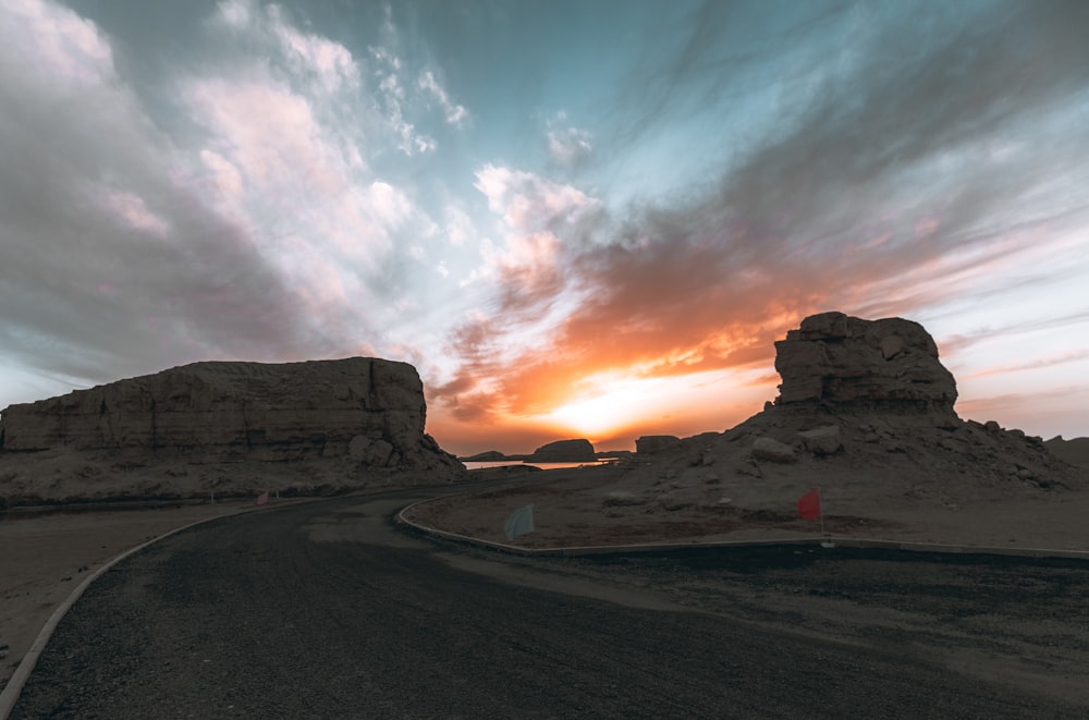 the sun is setting over a desert road