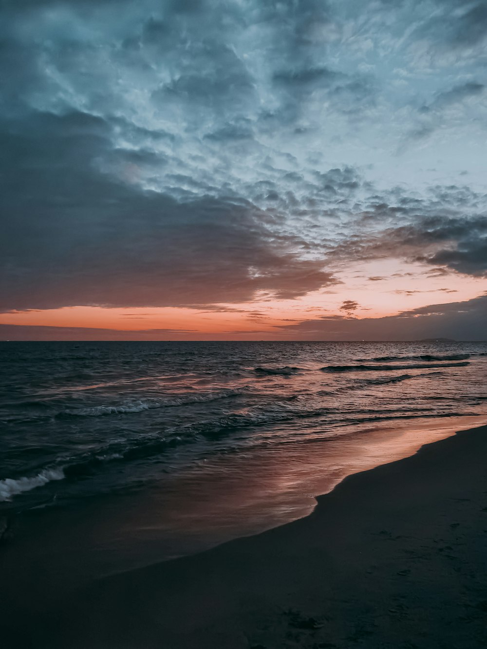 ocean waves crashing on shore during sunset