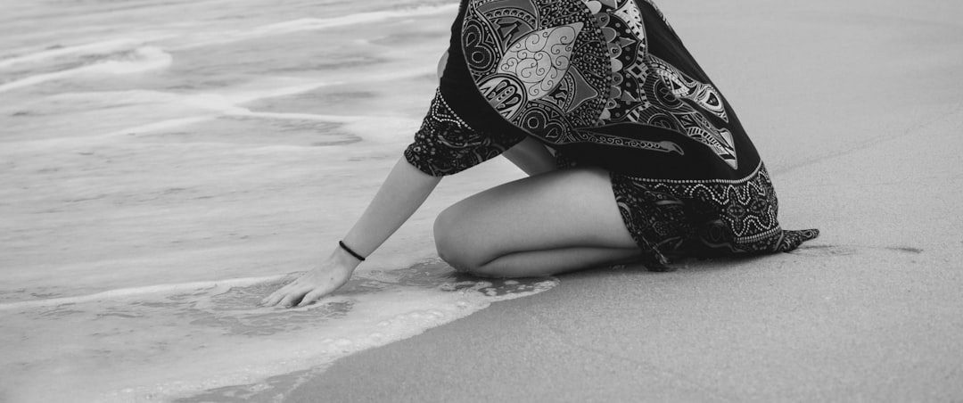 woman in black and white floral dress sitting on concrete pavement