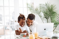 Close-up of a dad smiling as his child shares a funny story during a podcast recording.