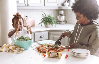 woman in white long sleeve shirt slicing pizza