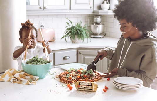 woman in white long sleeve shirt slicing pizza