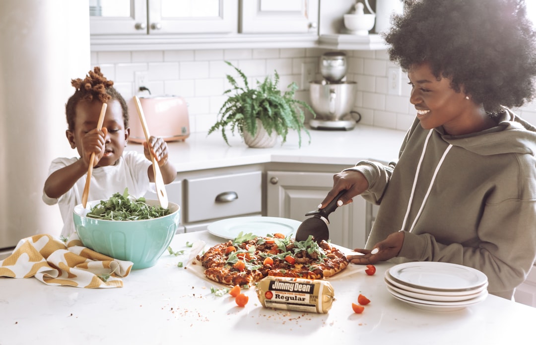 woman in white long sleeve shirt slicing pizza