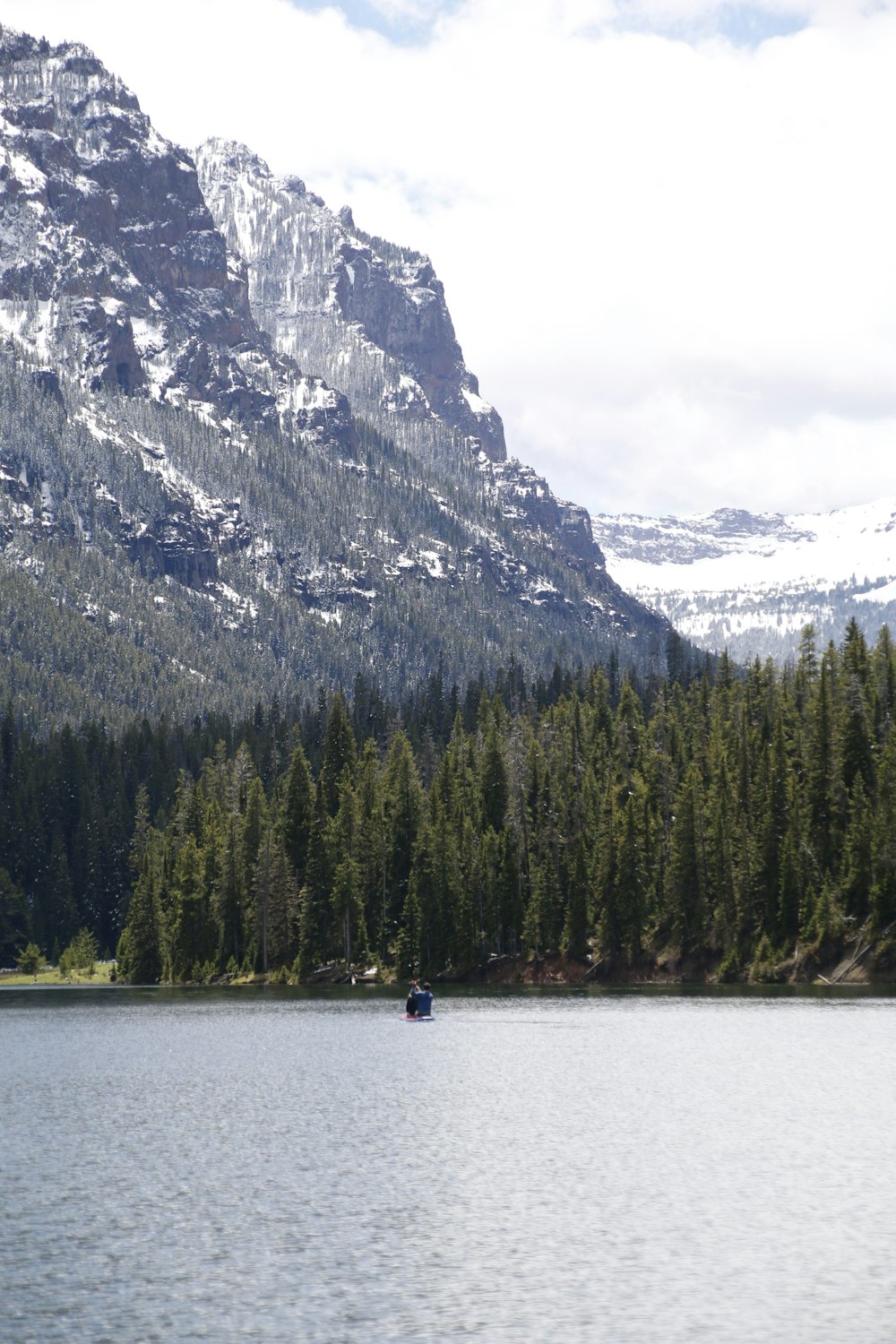 person riding on boat on lake near mountain during daytime