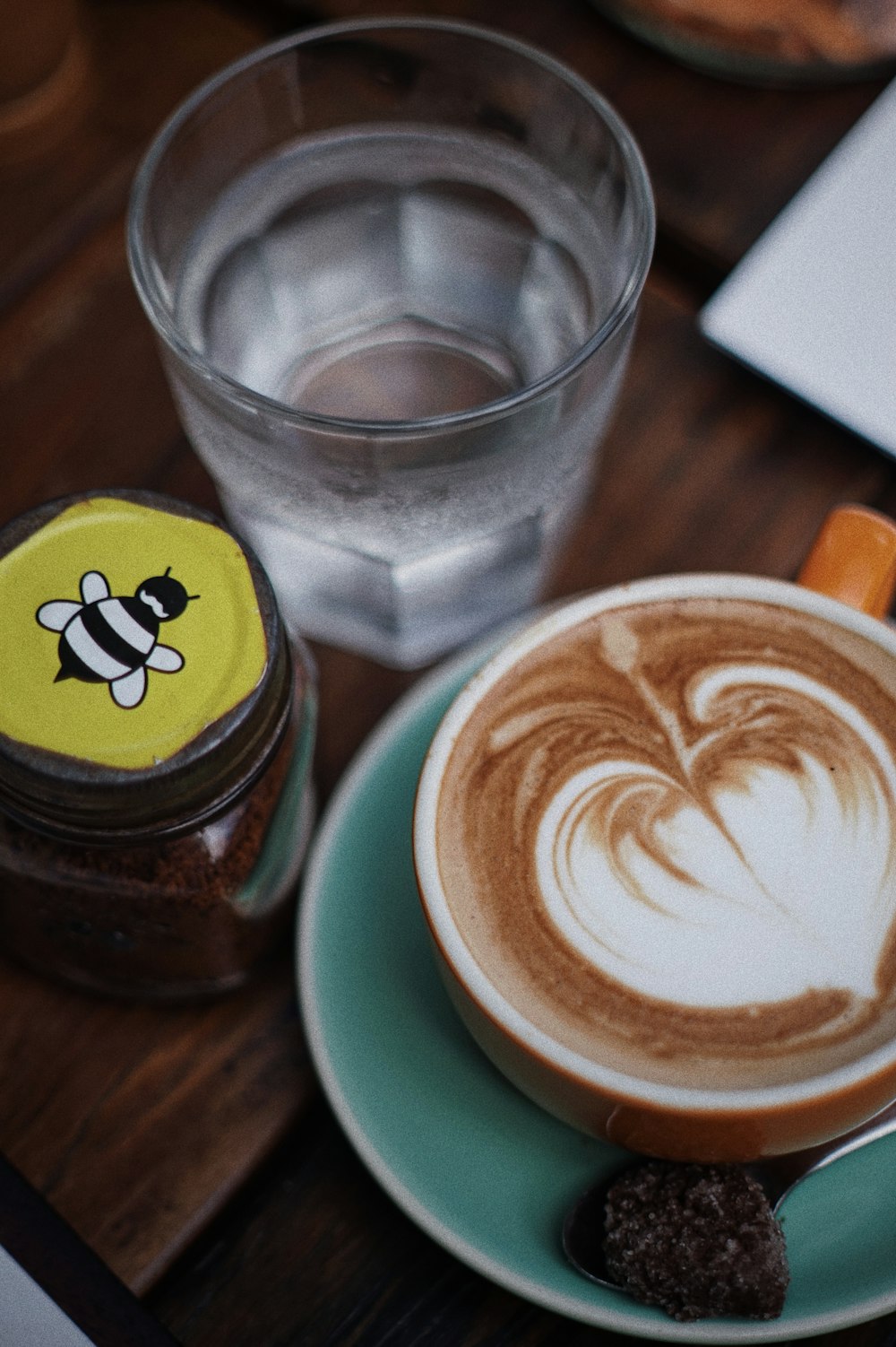 Cappuccino dans une tasse en céramique verte sur soucoupe à côté d’un verre à boire transparent