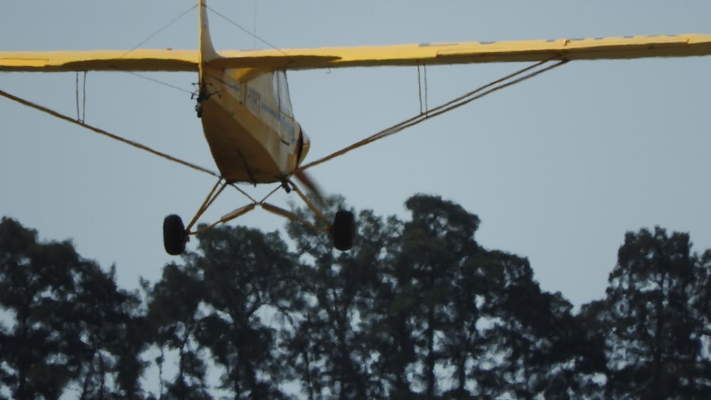 yellow and black helicopter flying over green trees during daytime