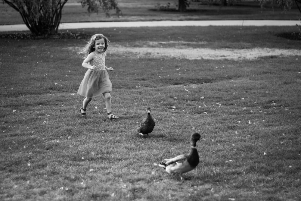 草原を歩くドレスを着た女の子のグレースケール写真
