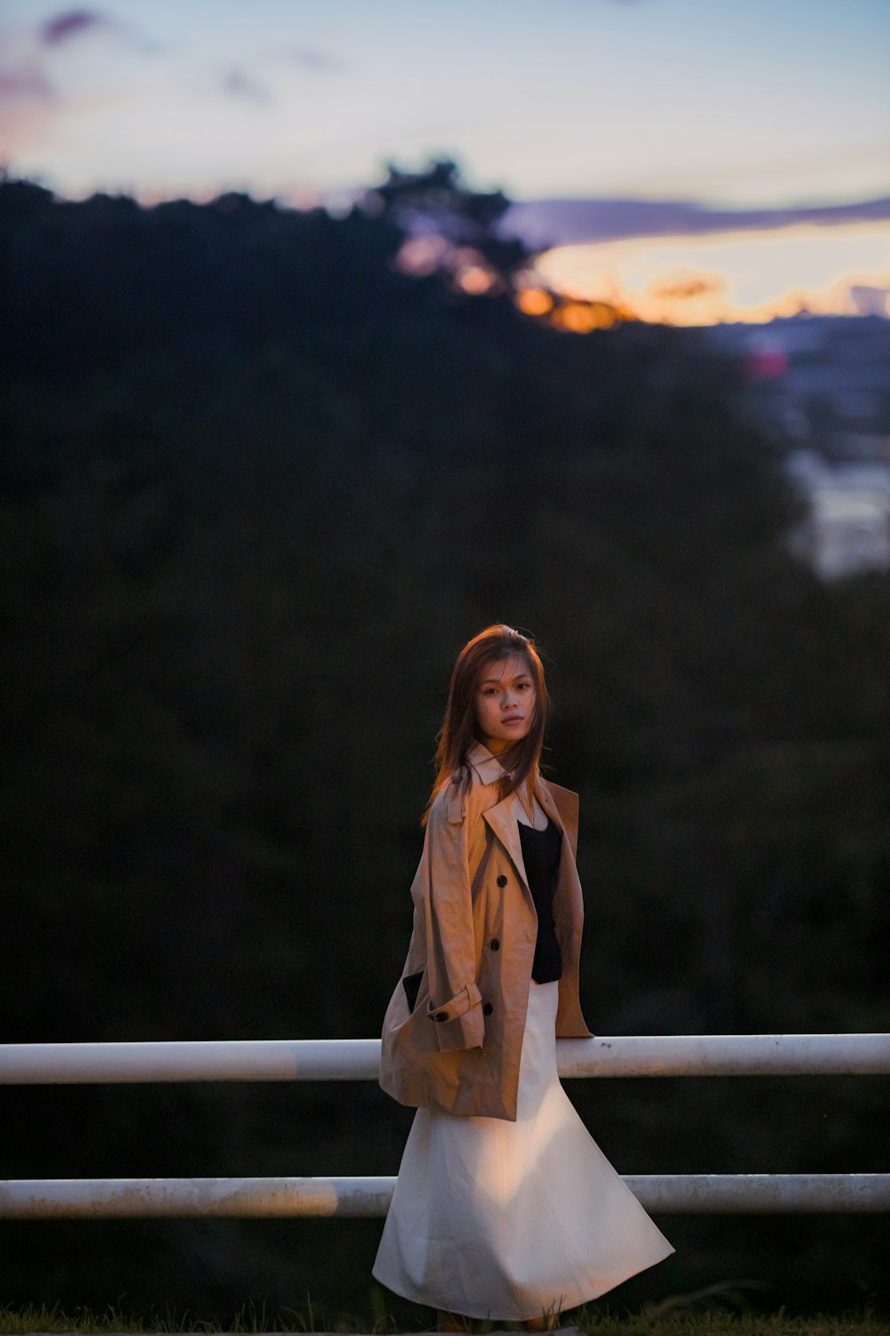 woman in brown coat standing on brown wooden fence during daytime