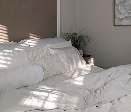 white bed linen near green plant