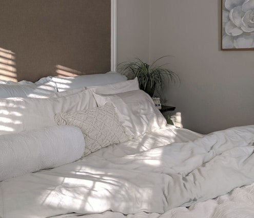 white bed linen near green plant