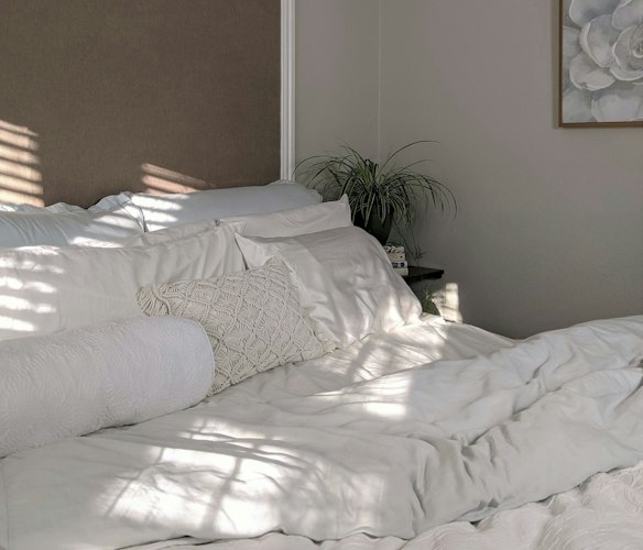 A tidy, sunlit spare bedroom with a made bed and simple furniture
