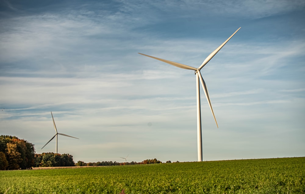 Weiße Windmühle auf grünem Rasenfeld unter weißen Wolken und blauem Himmel tagsüber