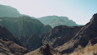 A panoramic view of rugged mountain cliffs under a clear blue sky in Europe.