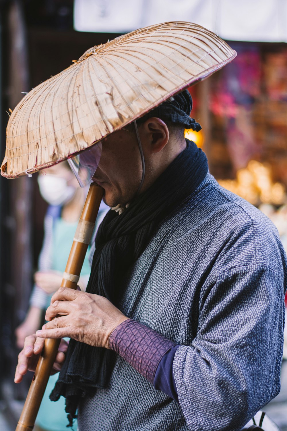 man in blue and white checked dress shirt wearing brown hat playing flute