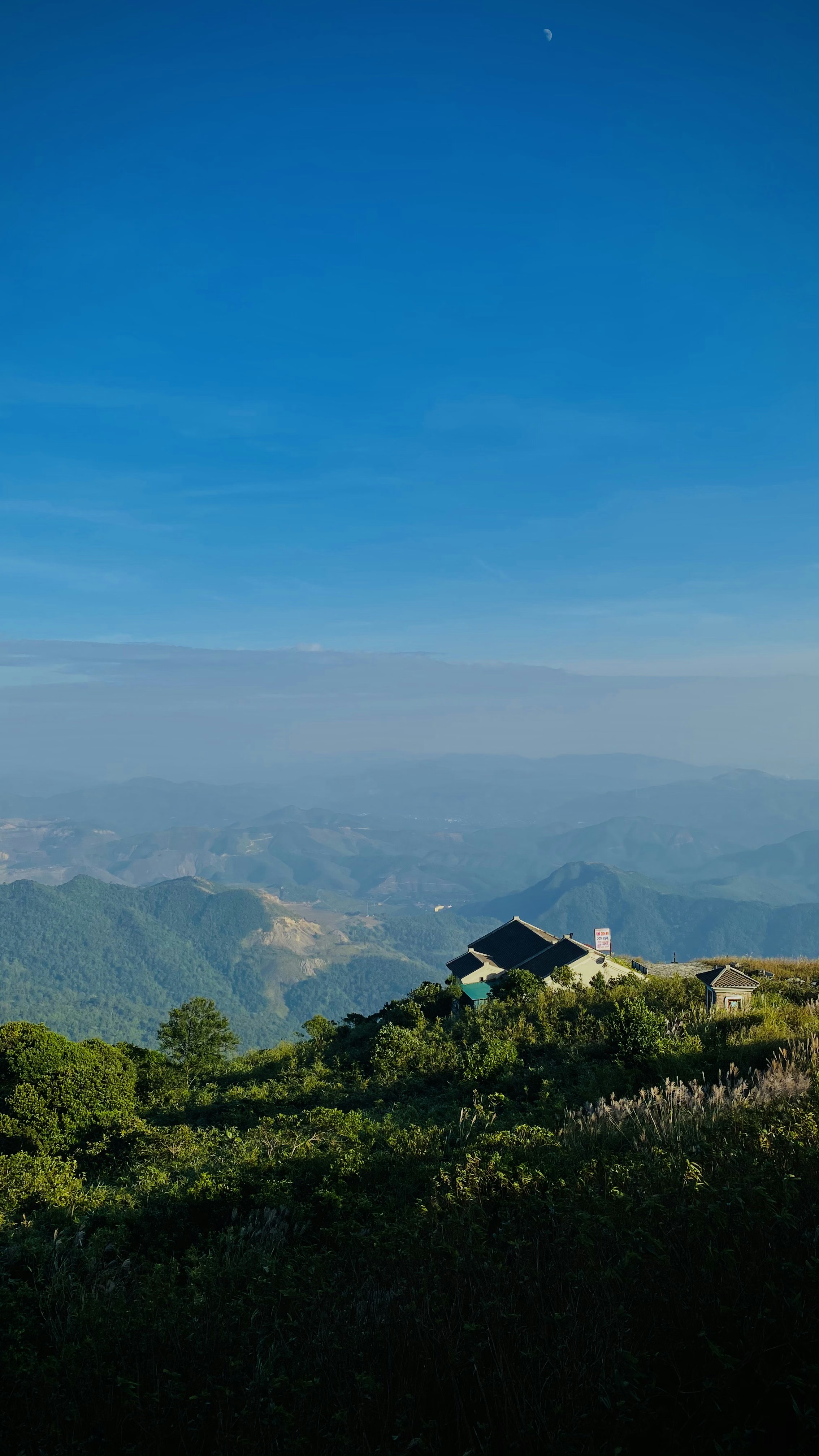white and black house on green grass field near mountains under blue sky during daytime