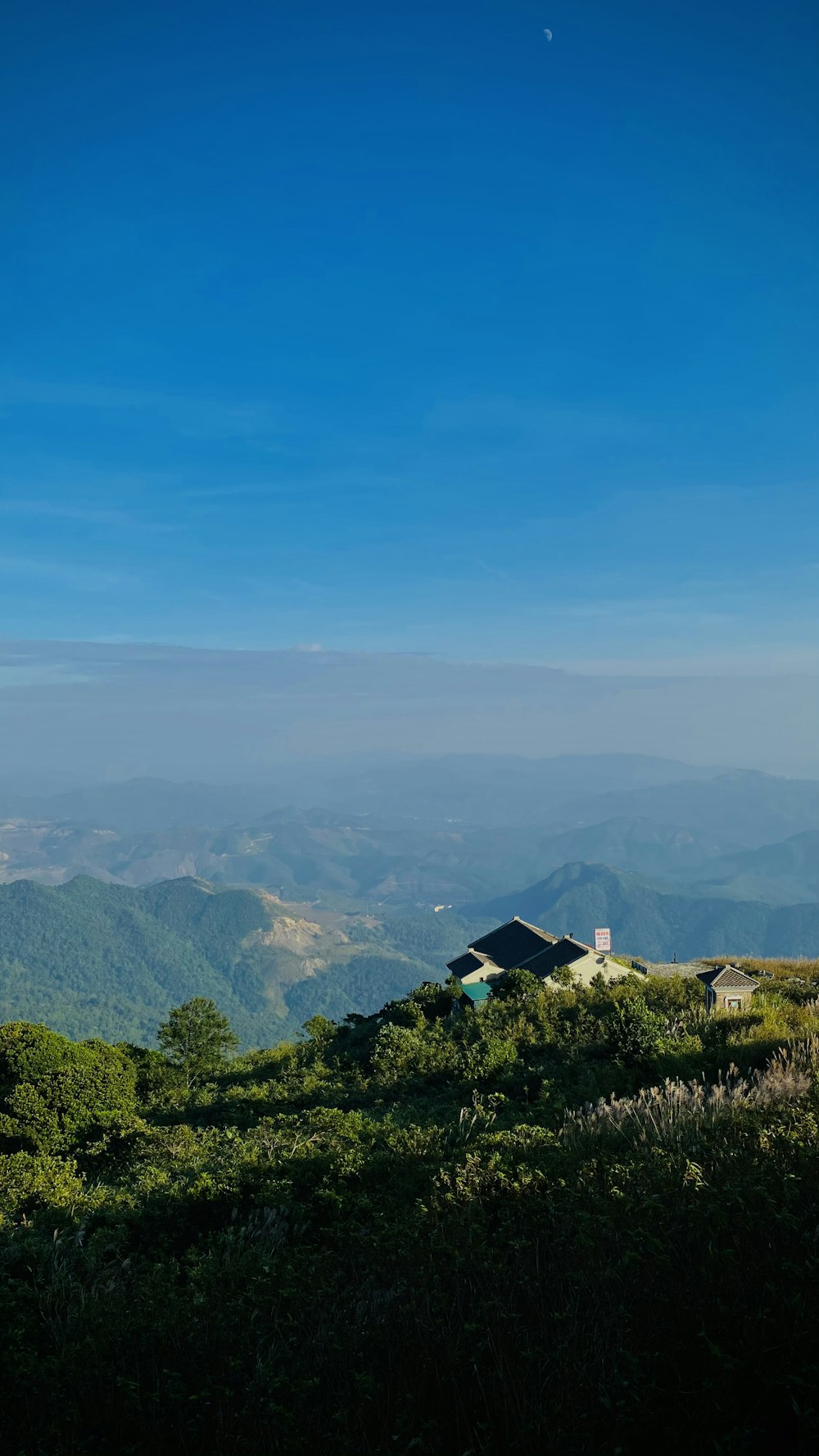 casa branca e preta no campo de grama verde perto das montanhas sob o céu azul durante o dia