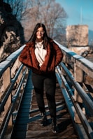 a woman standing on a bridge wearing a red jacket