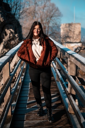 a woman standing on a bridge wearing a red jacket