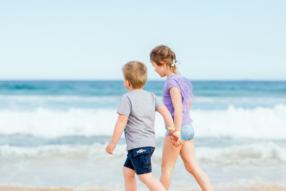 boy in white t-shirt and blue shorts standing on seashore during daytime