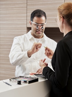 An ortho dontist in white dress shirt wearing black framed eyeglasses with patient