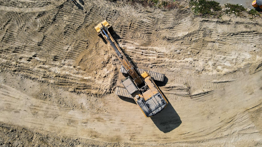 black and yellow heavy equipment on brown rock formation during daytime