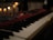 Close-up of a vintage synthesizer and drum kit in a warmly lit studio environment.