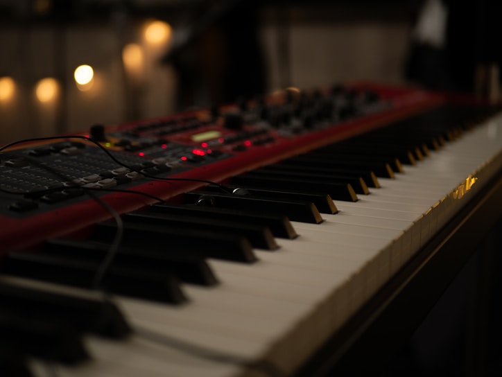 Close-up of vintage analog synthesizers and drum machines glowing softly in a dimly lit studio.